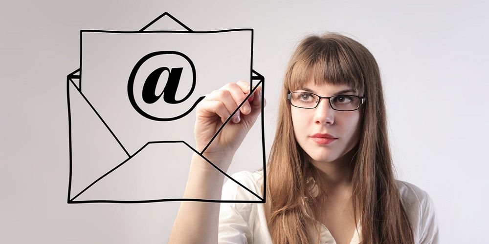 A girl drawing in front of her a letter with an email logo on a paper