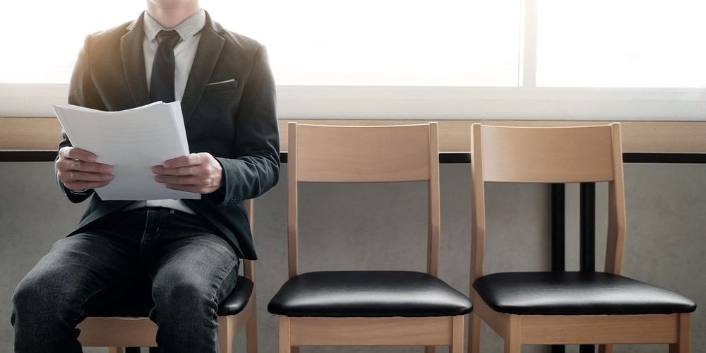 three chairs and a man sitting on the first chair with some papers on his hand