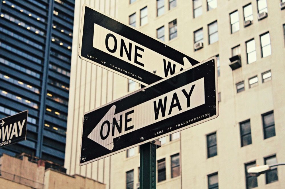 Two one-way street signs pointing in opposite directions, symbolizing a one-way job offer
